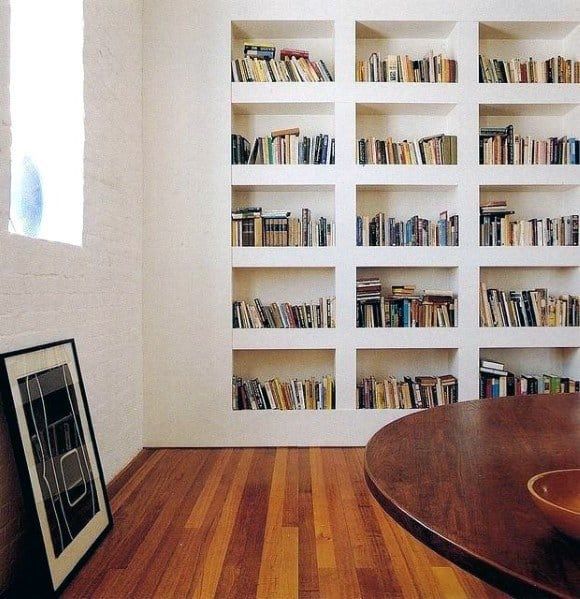 an empty room with bookshelves and a wooden table in the foreground