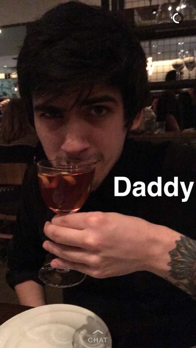 a man holding a wine glass in front of his face with the words daddy on it