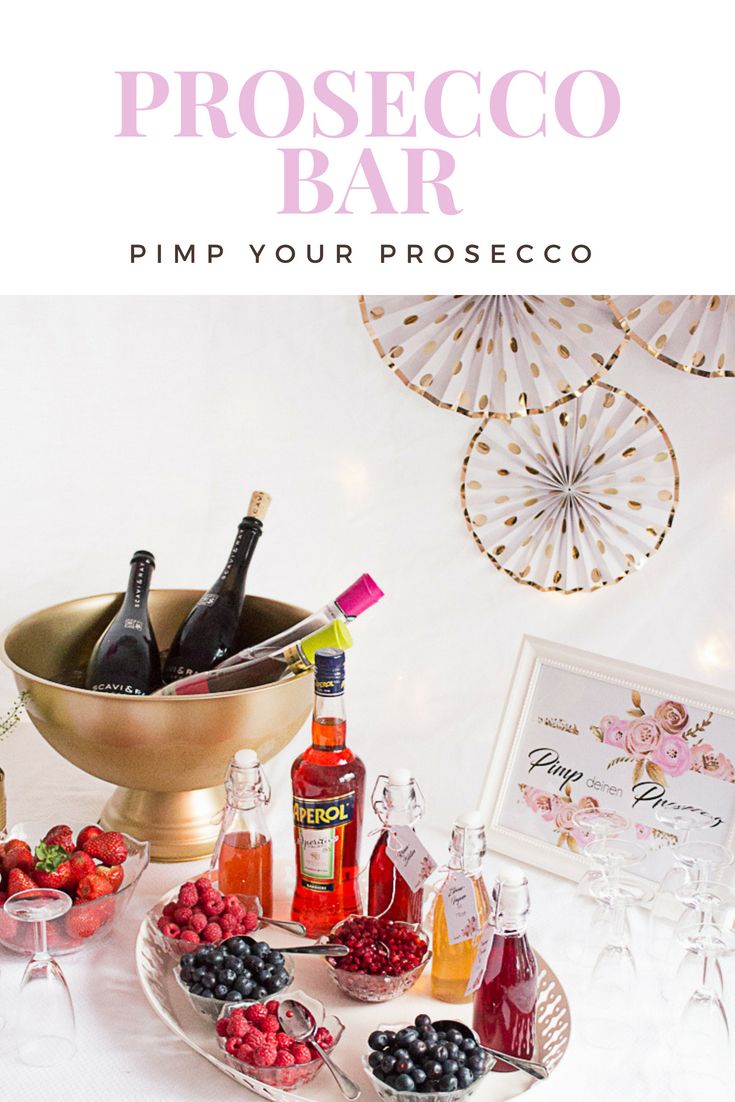 a table topped with bottles of wine and fruit next to a bowl filled with raspberries