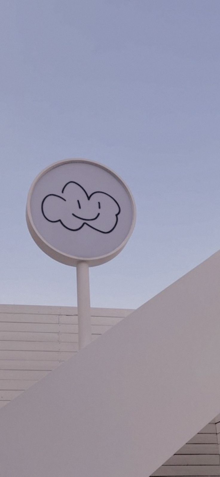 a white sign with a smiley face drawn on it's side next to a building