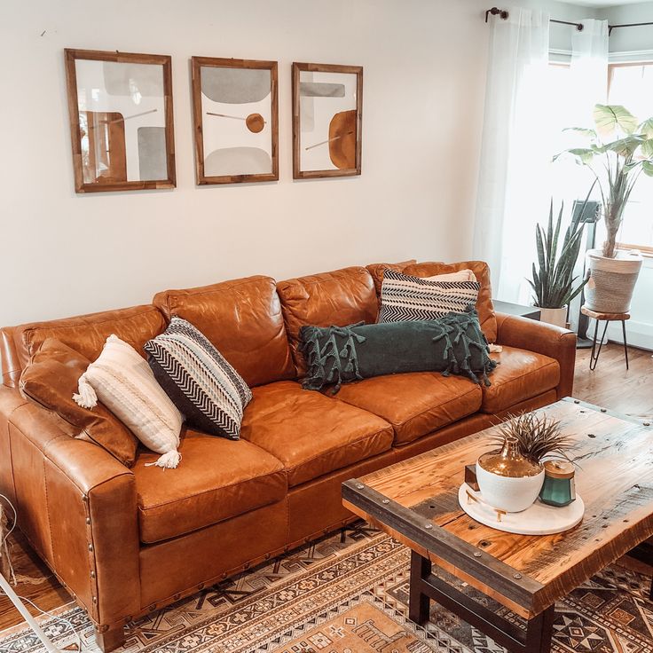 a brown leather couch sitting in a living room next to a coffee table and potted plant