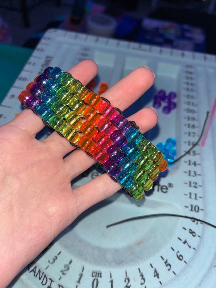 a person's hand holding a multicolored ring on top of a scale