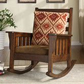 a rocking chair with a pillow on top of it in front of two framed pictures