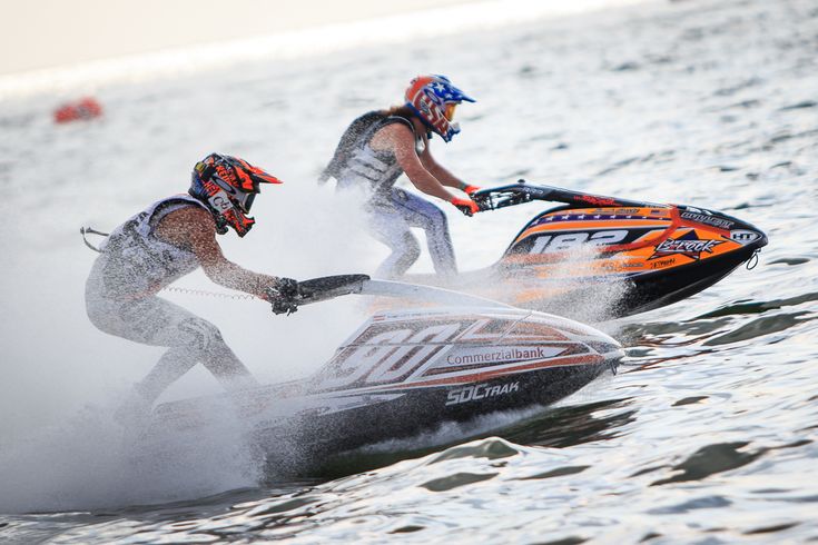 two men riding jet skis on top of water near each other in the ocean