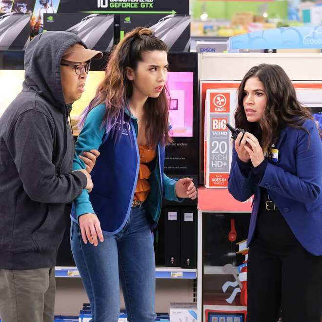 two women and a man standing in front of a vending machine talking to each other