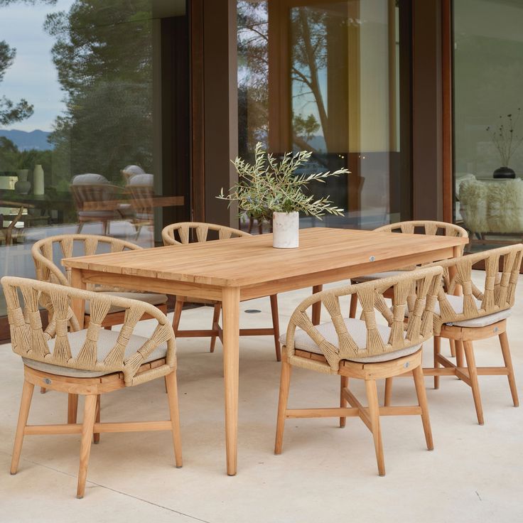 a wooden table with six chairs and a potted plant sitting on top of it