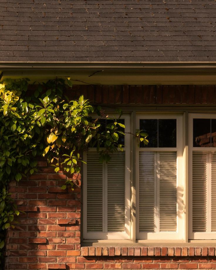 an open window with white shutters on a brick building