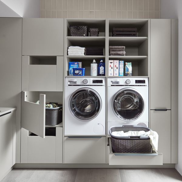 a washer and dryer in a small room with shelves on the wall behind them