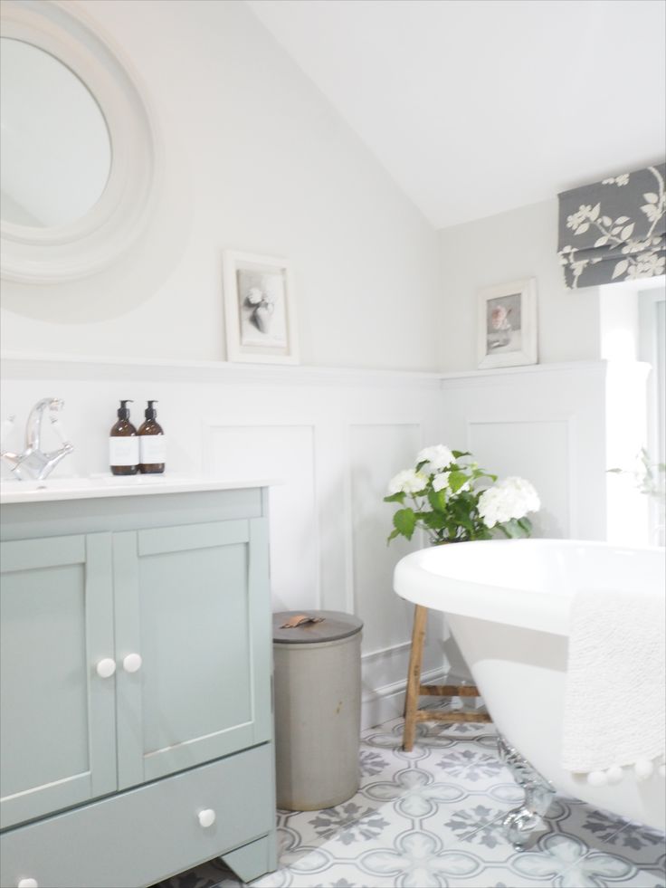 a white bath tub sitting next to a sink in a bathroom under a round mirror