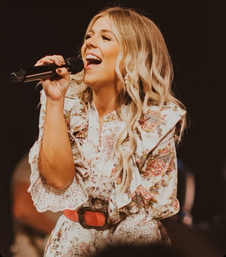 a woman singing into a microphone on stage