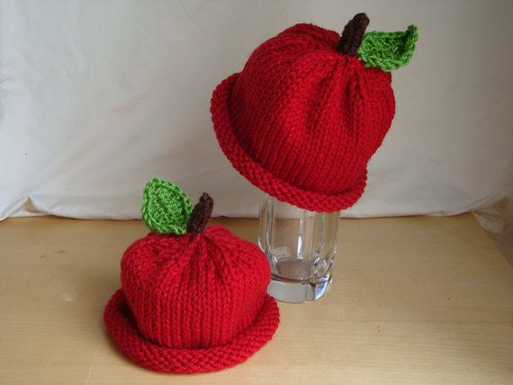 two knitted apples sitting on top of a table next to a glass filled with water