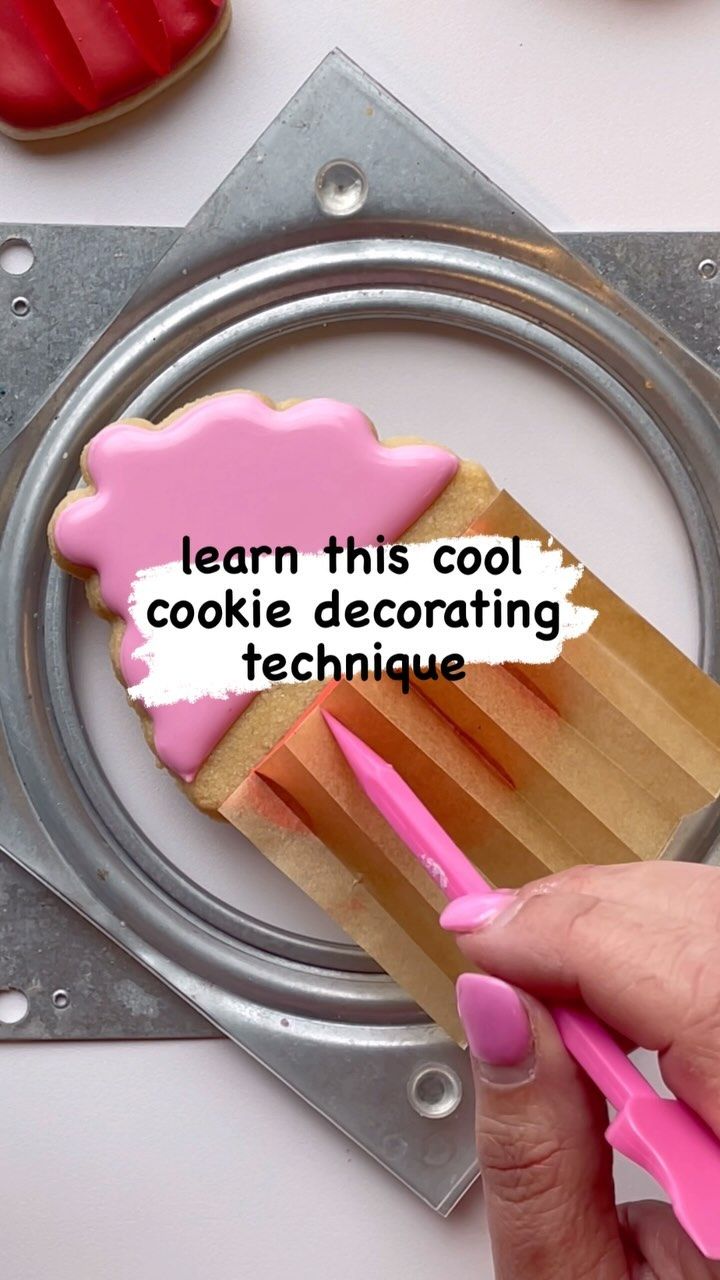 a person holding a pink toothbrush on top of a piece of cake with the words learn this cool cookie decorating technique