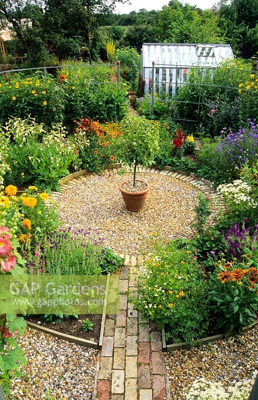 a garden filled with lots of different types of flowers and plants on top of gravel