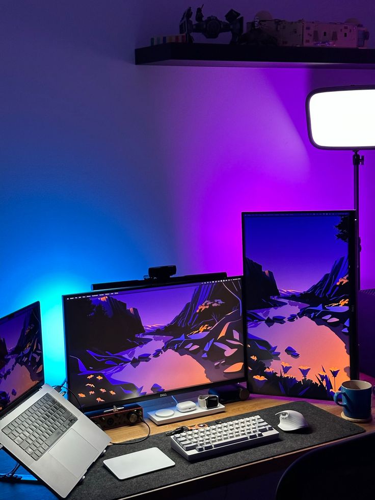 three computer monitors sitting on top of a desk next to a laptop and monitor screen