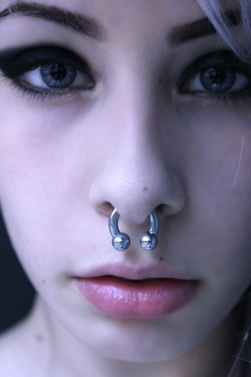 a woman with piercings on her nose and nose ring in front of her face