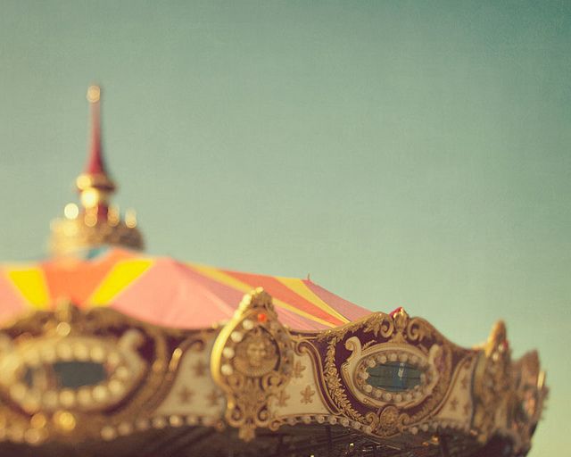 an ornately decorated carnival ride with a red and yellow striped umbrella in the foreground