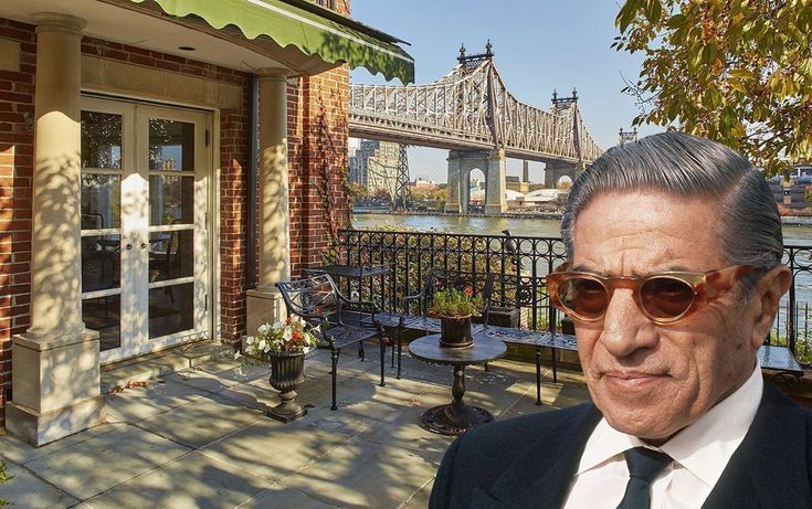 a man wearing sunglasses and a suit standing in front of a building with a bridge in the background