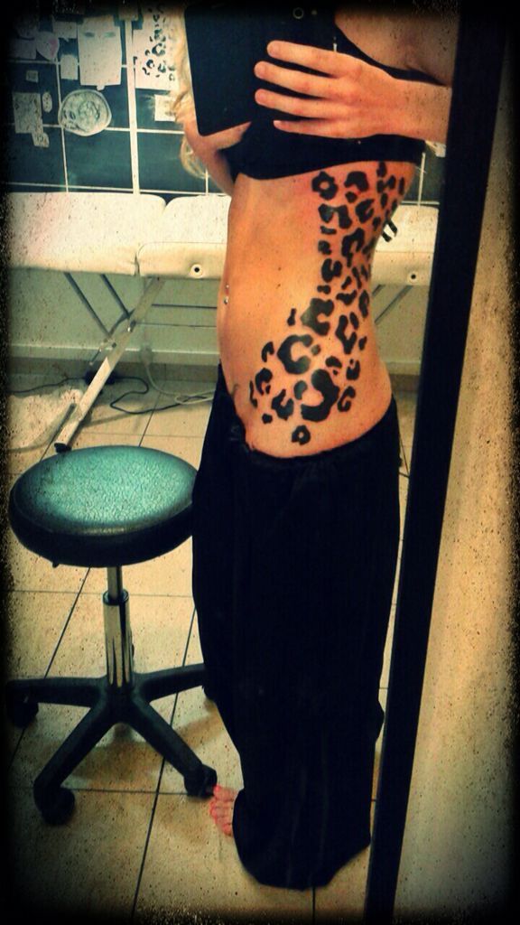 a woman with a leopard print tattoo on her stomach is standing in front of a mirror