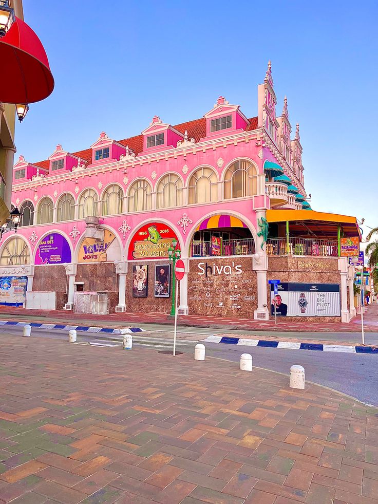 an old pink building on the corner of a street in front of a red and yellow awning