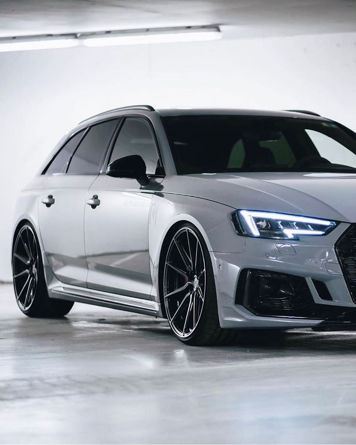 the front end of a white car in a parking garage with black rims and chrome wheels