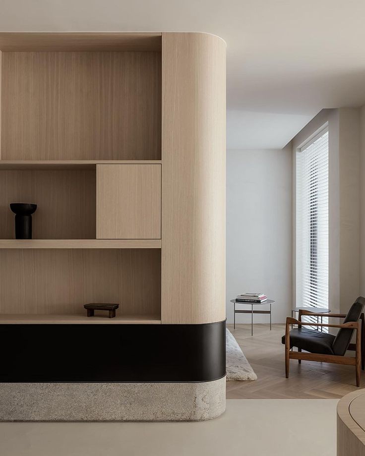 a living room filled with furniture and a book shelf next to a chair in front of a window