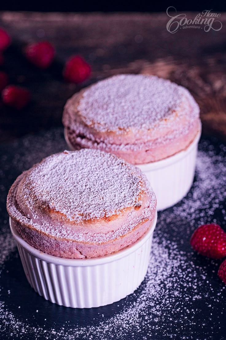 two desserts with powdered sugar on top and raspberries in the background