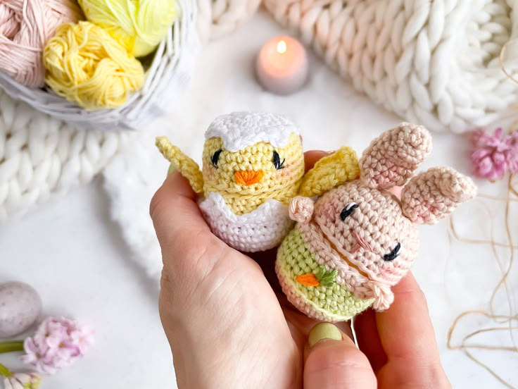 a person holding two small crocheted animals in their hands next to some flowers