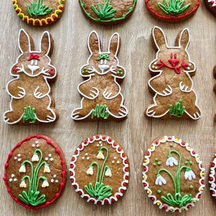 twelve decorated cookies are arranged on a table with flowers and bunnies in the shape of rabbits