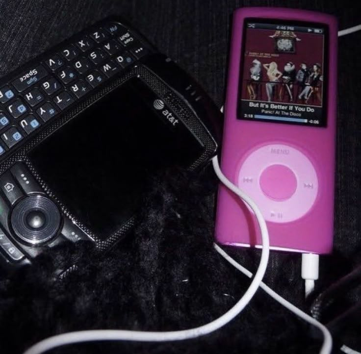 an ipod is plugged into a charger next to a cell phone and mp3 player