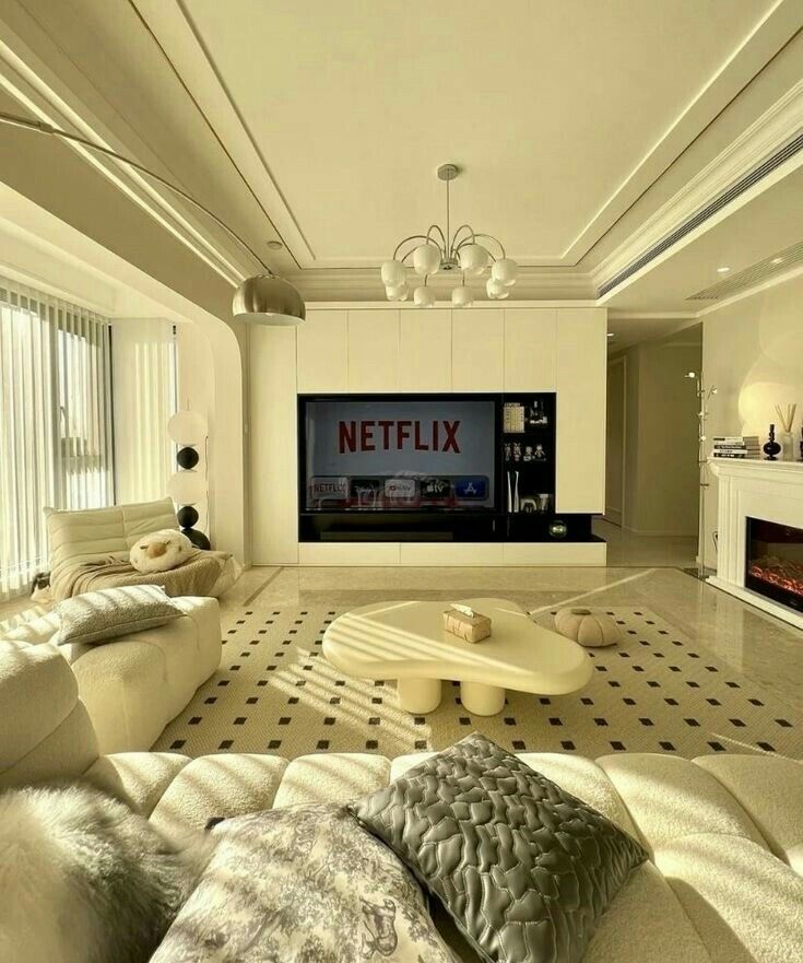 a living room with white couches and a large flat screen tv mounted to the wall