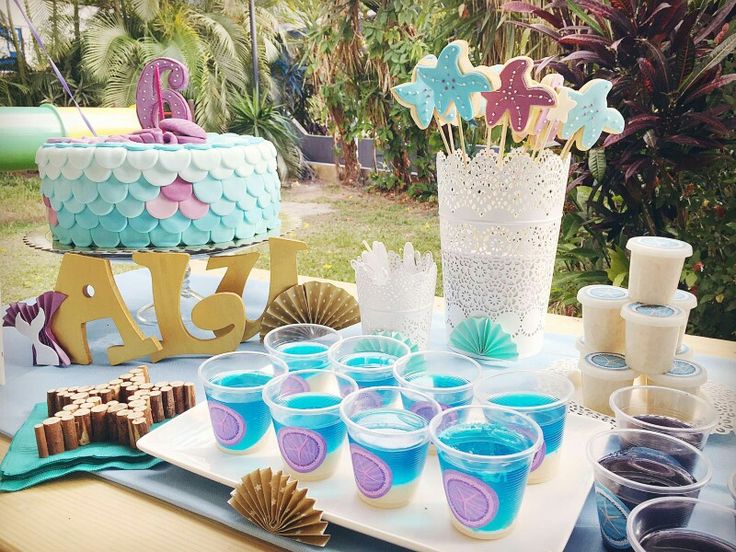 a table topped with cupcakes covered in blue frosting and mermaid tail decorations