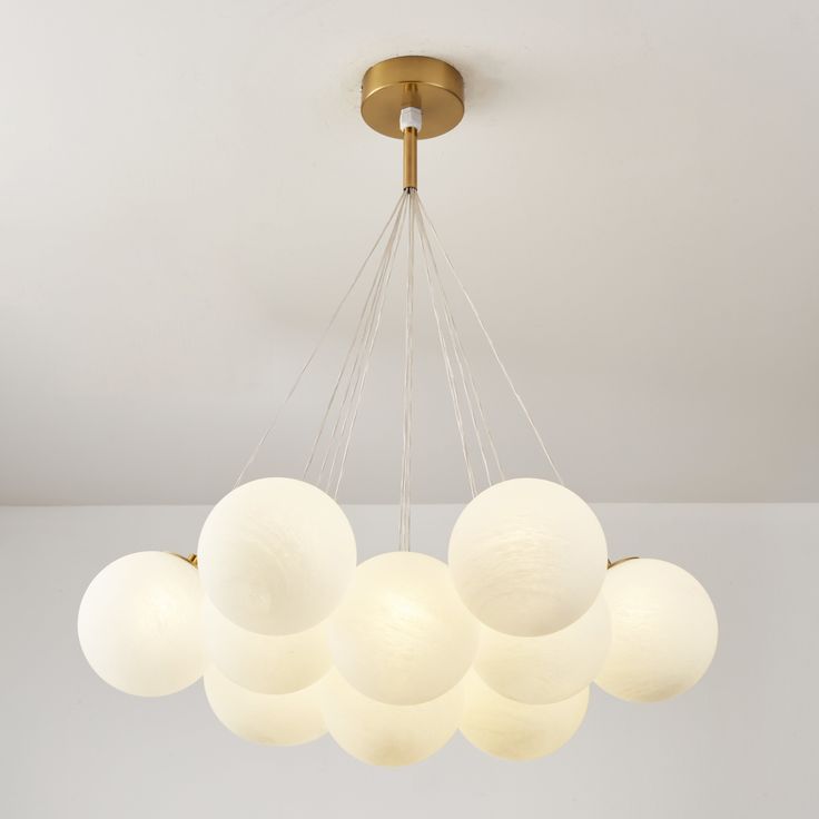 a chandelier with five white balls hanging from it's center and four lights on each side