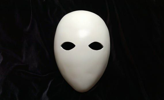 a white mask with two black eyes on a black background