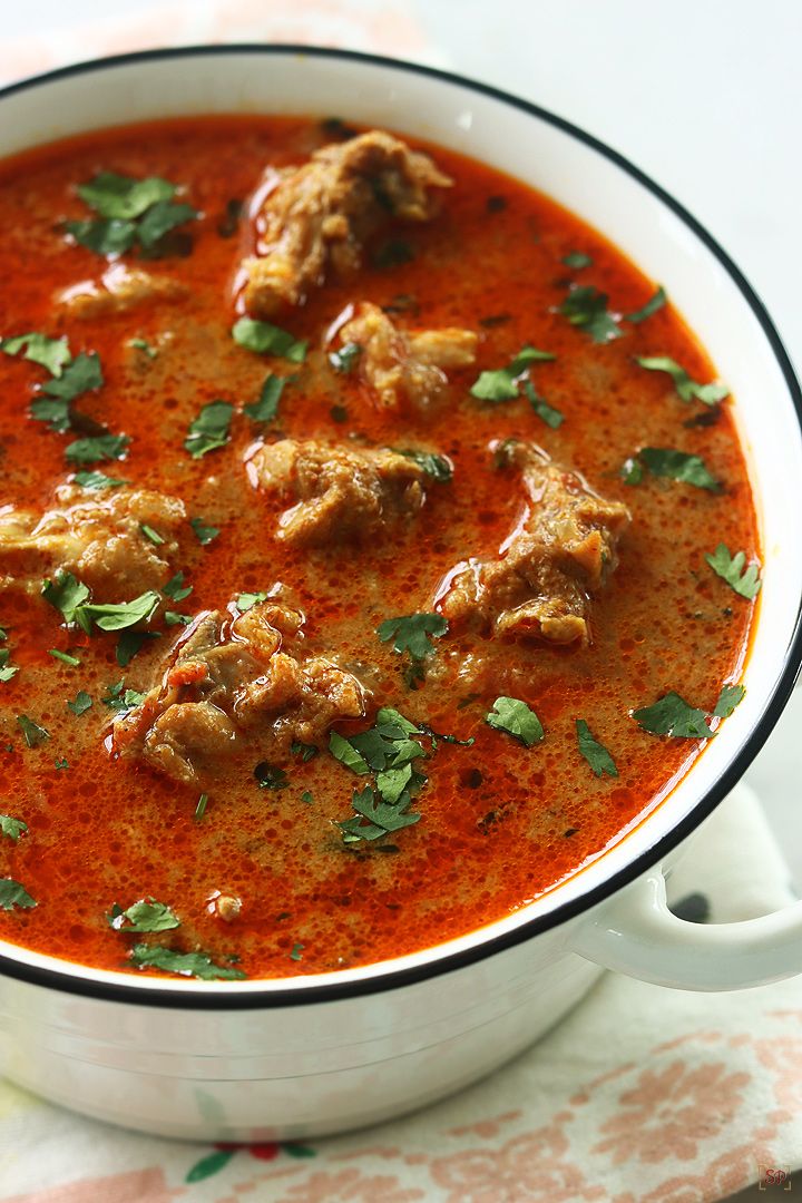 a white bowl filled with meat and tomato soup