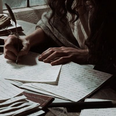 a person writing on paper with a pen in their hand and several other papers around them