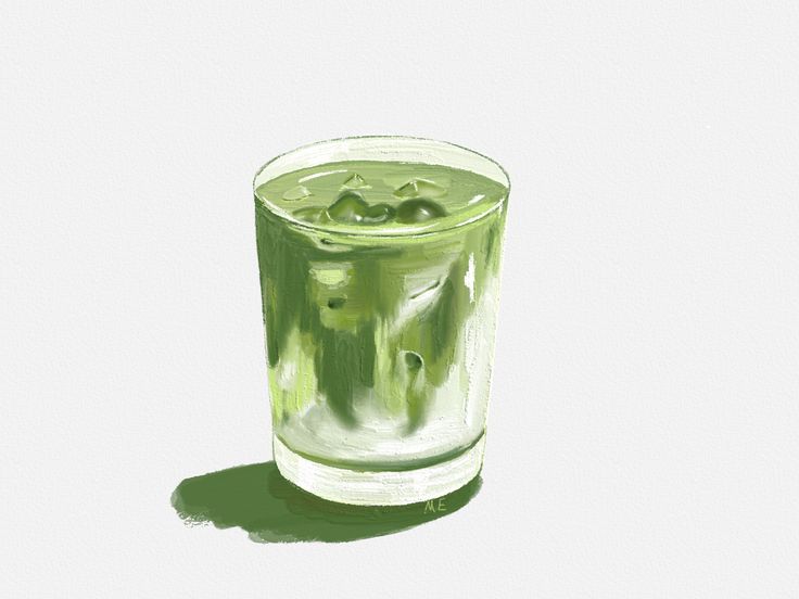 a glass filled with green liquid sitting on top of a table