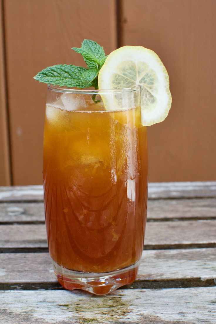 a glass filled with ice and lemon sitting on top of a wooden table