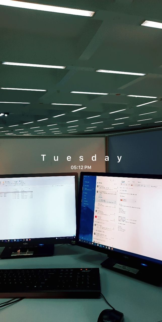 two computer monitors sitting next to each other on top of a desk in an office