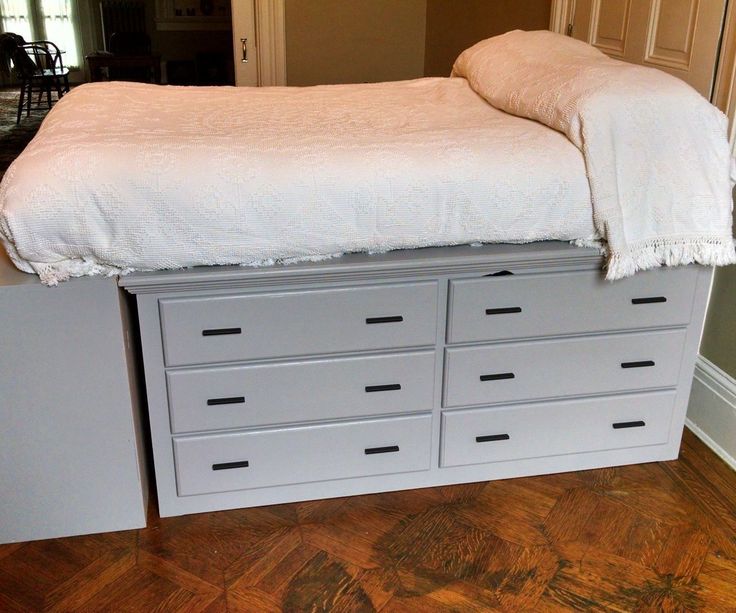 a white bed sitting on top of a wooden floor next to a dresser with drawers