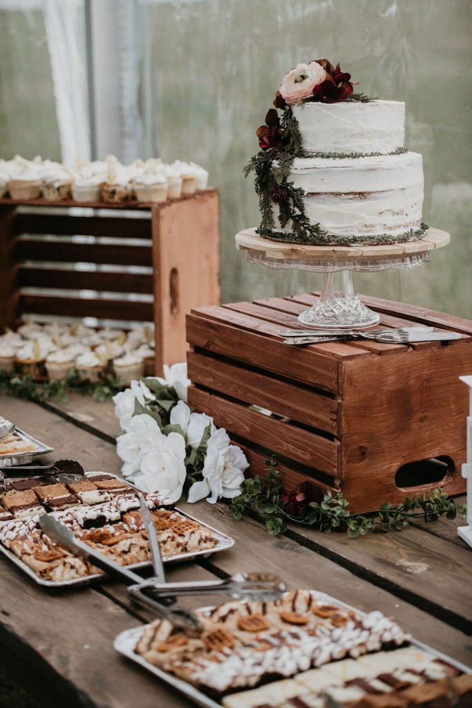 a table topped with lots of desserts next to wooden boxes filled with cakes and pies