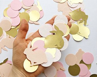 a hand is holding up some pink and gold confetti pieces with hearts on them