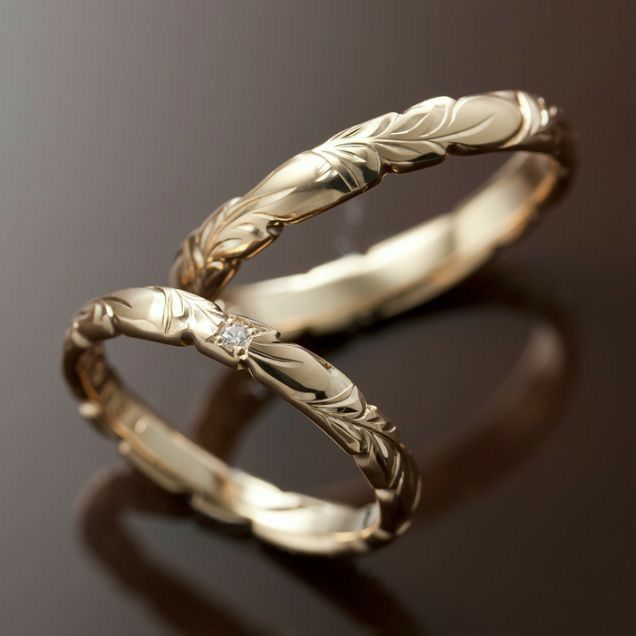 two gold wedding bands with leaves and diamonds on black background, close up view photo