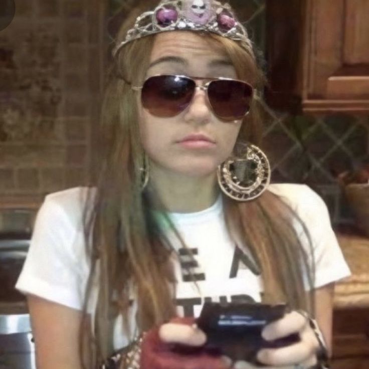 a woman with sunglasses and a tiara holding a cell phone