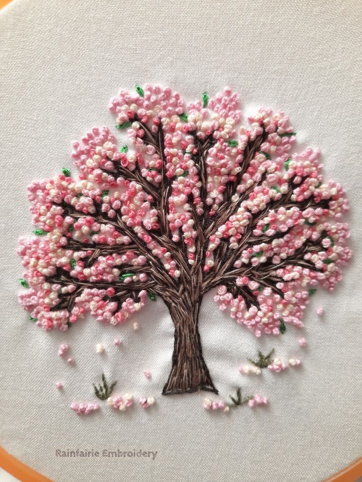 a hand embroidered tree with pink and green leaves