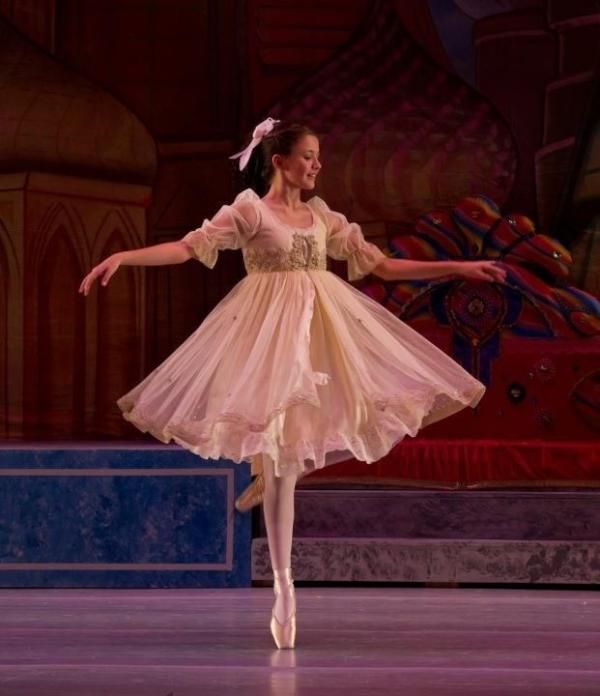 a ballerina in a pink dress is performing on stage