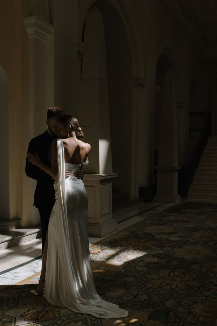 a man and woman in formal wear standing next to each other with their arms around each other