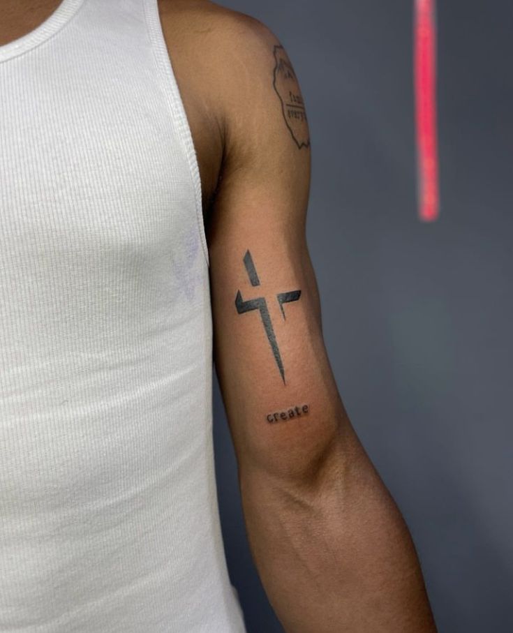 a man with a cross tattoo on his arm is looking at the camera while wearing a white tank top