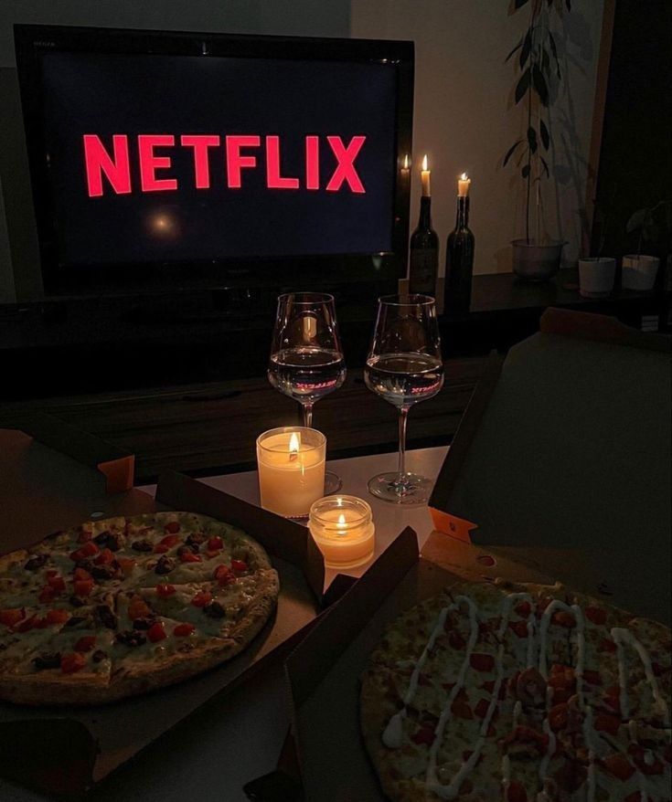 two pizzas sitting next to each other in front of a tv with the netflix logo on it