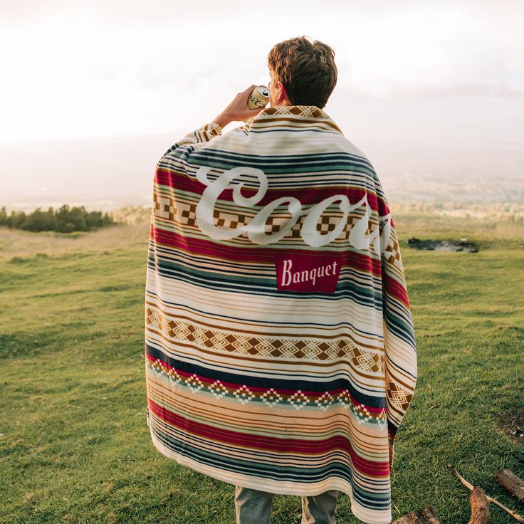 a person standing in a field with a blanket over their shoulders that says coco banquet