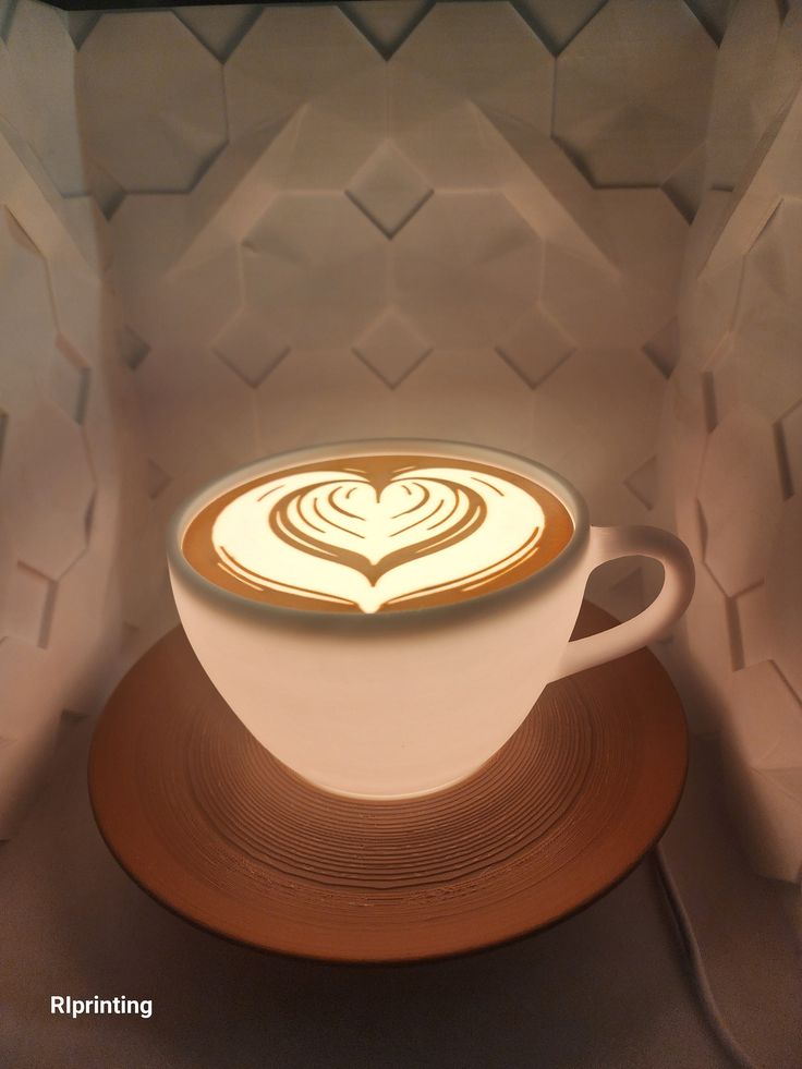 there is a coffee cup with a heart in the foam on it's top